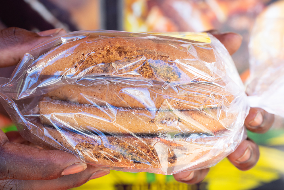 four cookies wrapped in clear plastic held up by hands with peach nail polish