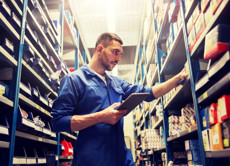 man in blue worker's jumpsuit searching for parts in plastic boxes on shelves